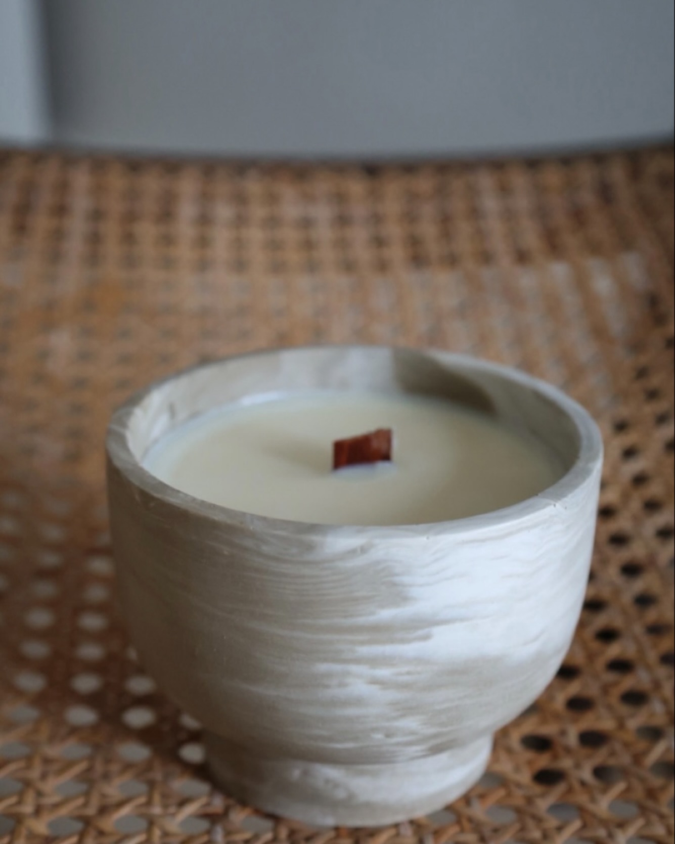 A marbled vessel candle with a visible wood wick.